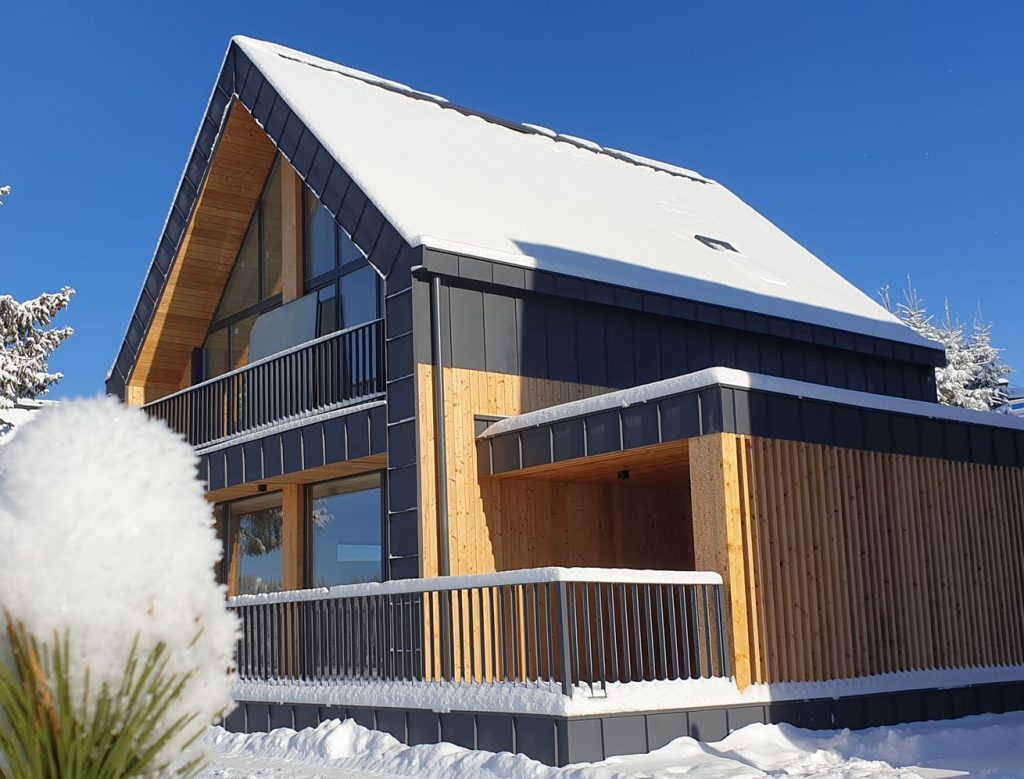 Modern eco house in snowy landscape, highlighting excellent insulation and reduced energy needs with straw panel walls.