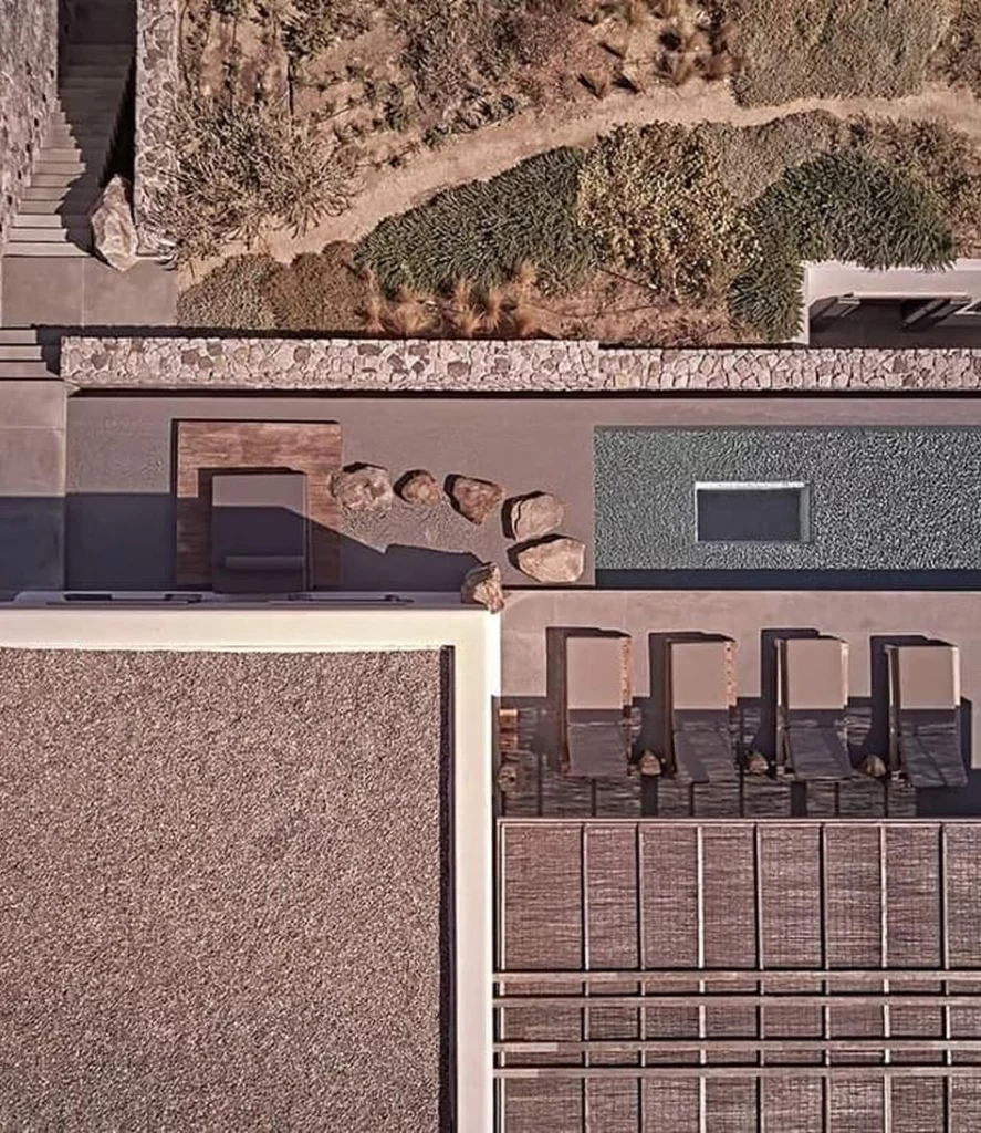 Aerial view of an eco-friendly house with natural landscaping, stone walls, and durable panel construction resistant to environmental factors