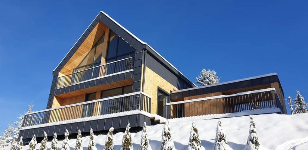 Modern house built with straw-insulated eco-panels, featuring unique architectural design, large windows, and custom wooden finishes